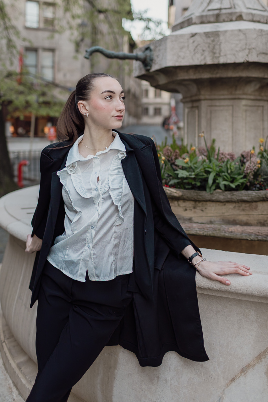 Model sitting by a fountain at sunrise in Geneva’s Old Town